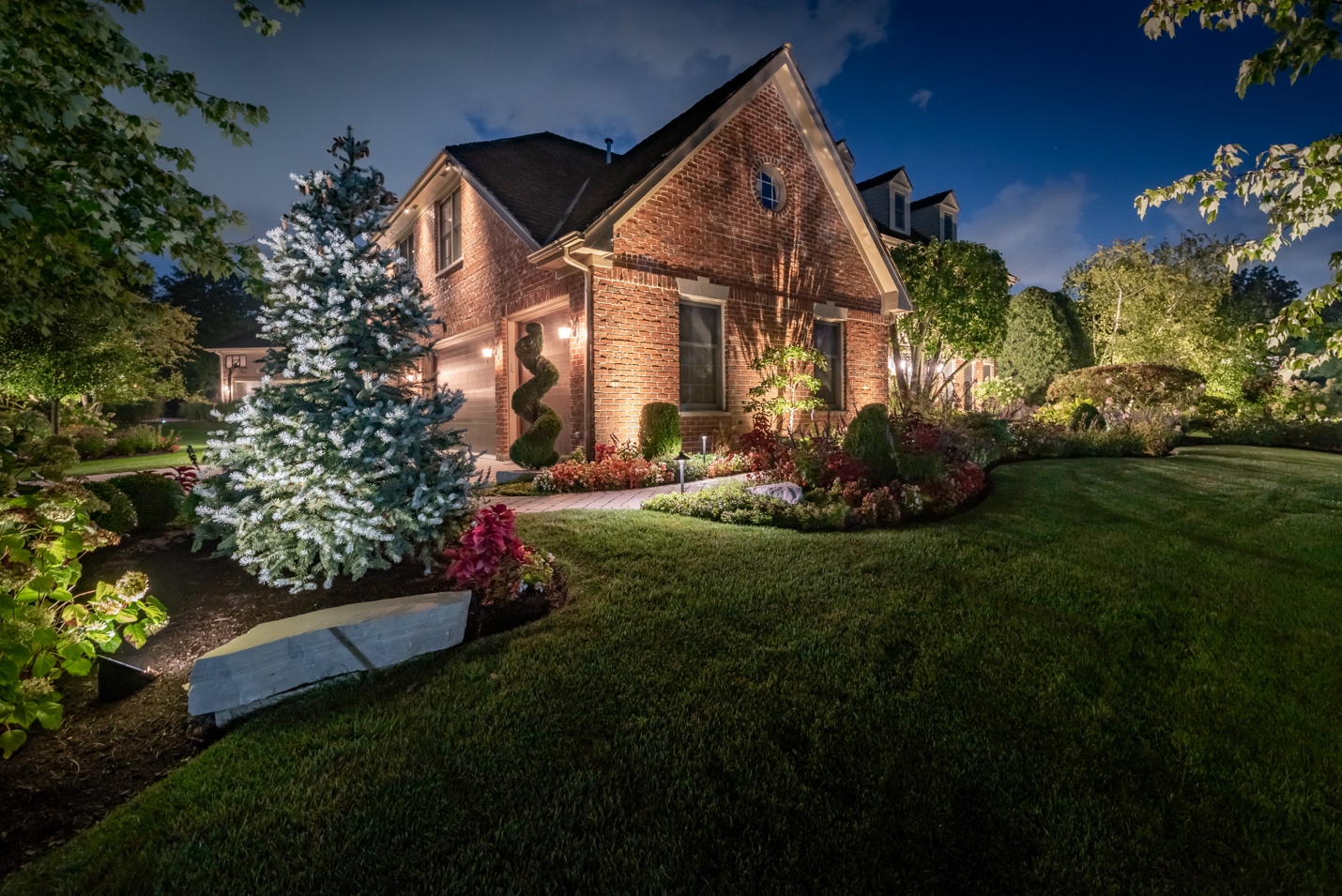 A house with a lawn and trees at night

Description automatically generated